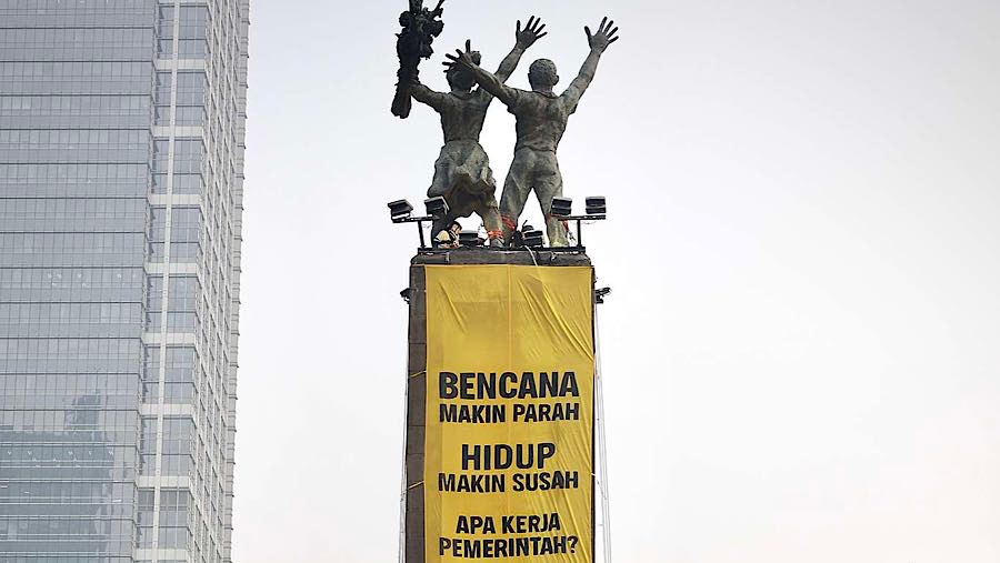 Greenpeace Indonesia menggelar aksi membentangkan dua spanduk dari atas Patung Selamat Datang. (foto dok. Greenpeace Indonesia)