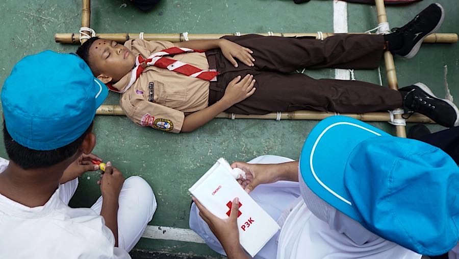 Anggota PMR dan Pramuka kemudian memberikan pertolongan pertama kepada siswa yang pingsan tersebut. (Bloomberg Technoz/Andrean Kristianto)