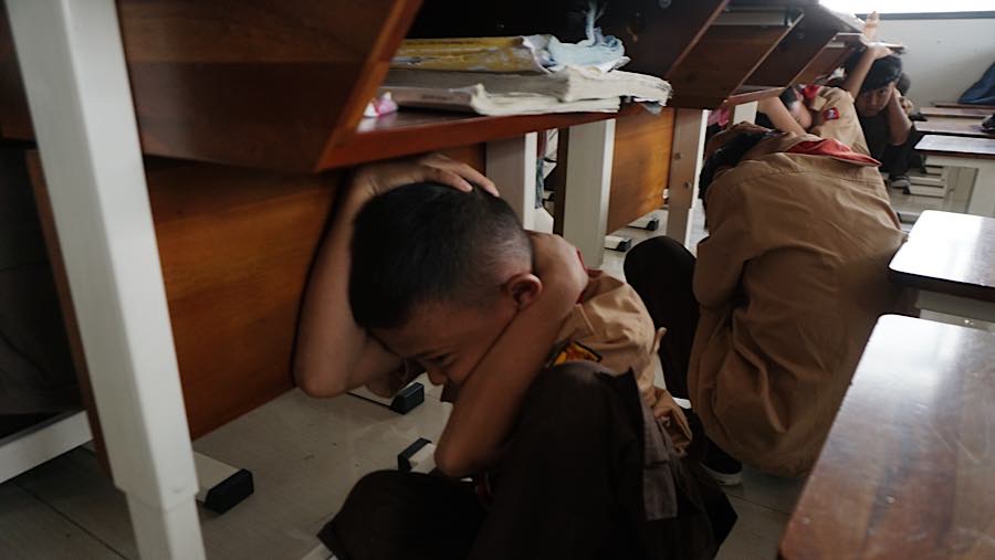 Suara bel mendadak memecah kegiatan belajar di SDN Pejaten Timur 11 dan para murid berlindung dibawah meja. (Bloomberg Technoz/Andrean Kristianto)