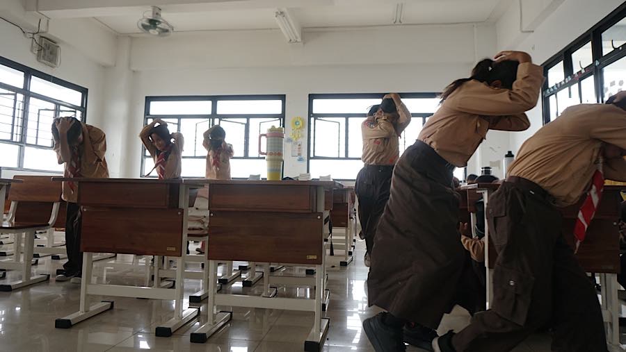 Tak lama kemudian mereka bergegas keluar  kelas sambil melindungi kepala dengan tangan atau tas. (Bloomberg Technoz/Andrean Kristianto)