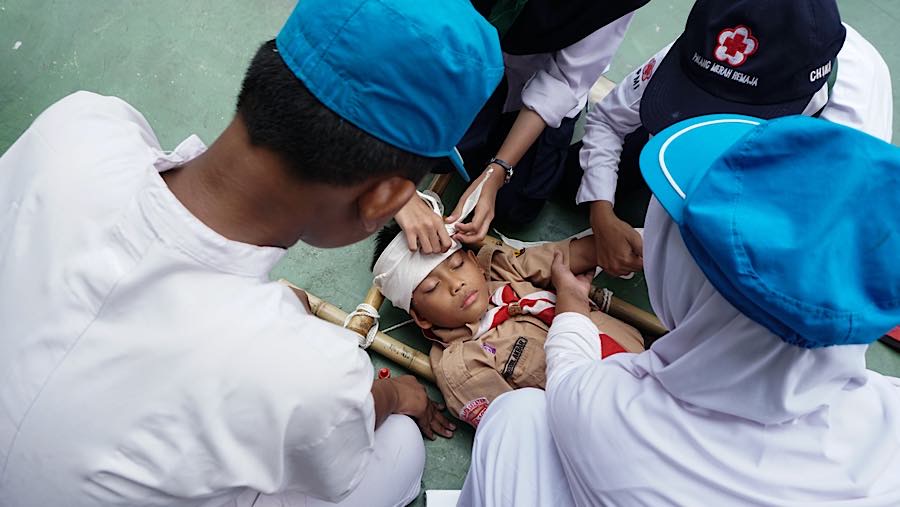 Mereka memasang perban pada bagian kepala dan kaki siswa yang disimulasikan mengalami luka. (Bloomberg Technoz/Andrean Kristianto)