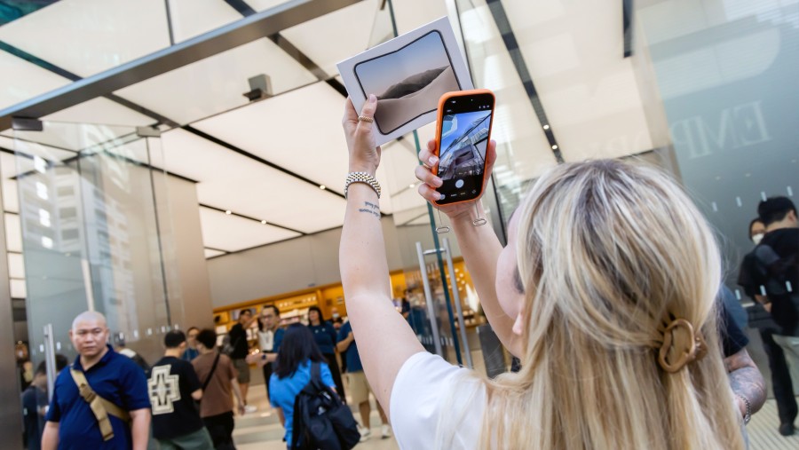 Pengunjung memotret iPhone Duo hasil pembelian perdana di jaringan ritel Apple Inc., di Canton Road, Hong Kong. (Paul Yeung/Bloomberg)