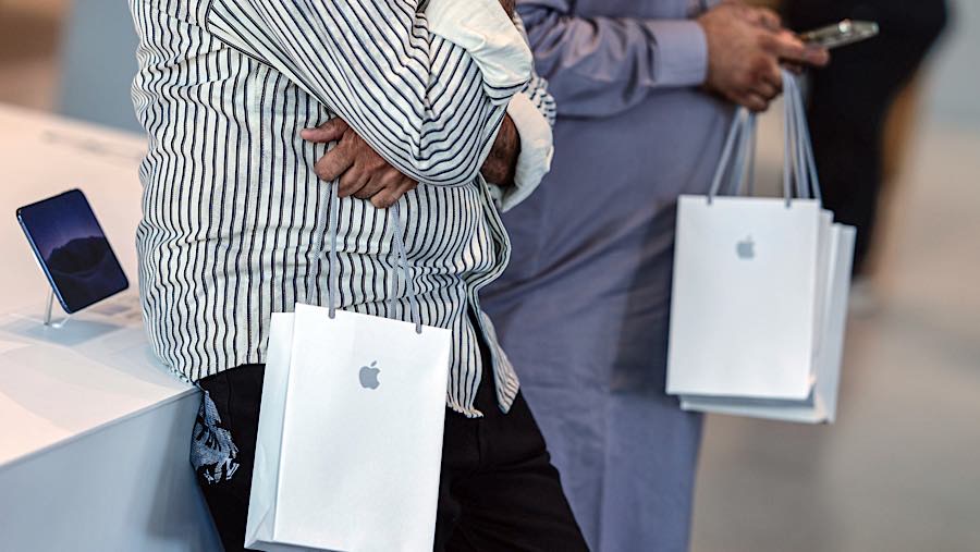 Para pelanggan memegang tas belanja Apple Inc. di Apple Store Bandra Kurla Complex (BKC), Mumbai, India, Jumat (23/10/2026). (Dhiraj Singh/Bloomberg)