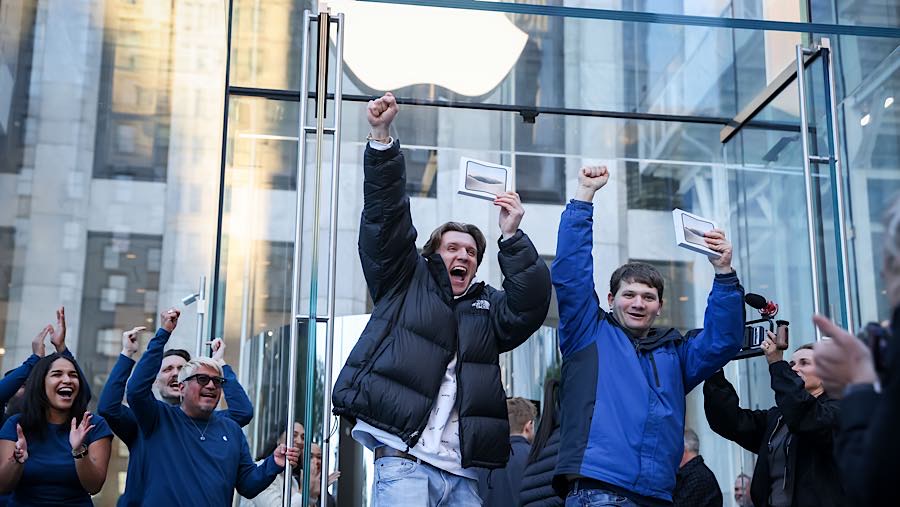 Pembeli pertama mengangkat iPhone Duo di toko Apple Fifth Avenue saat penjualan perdana di New York, AS, Jumat (23/10/2026). (Michael Nagle/Bloomberg)