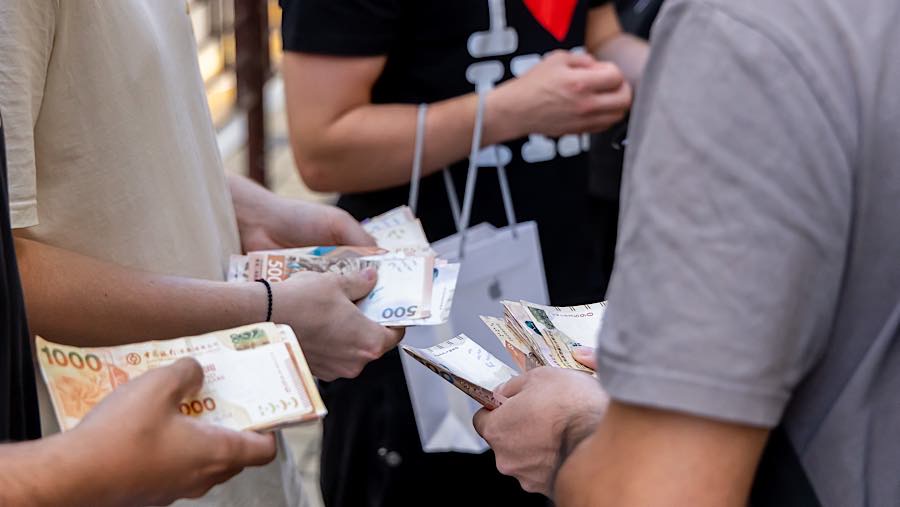 Reseller menghitung uang sambil memperdagangkan iPhone Duo di depan toko Apple di Hong Kong, Tiongkok, Jumat (23/10/2026). (Paul Yeung/Bloomberg)